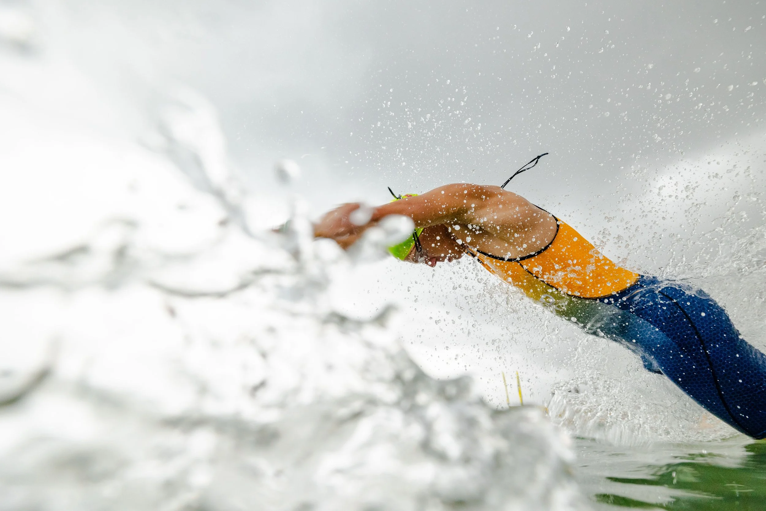 Triathlete diving through ocean wave at race start, captured by Stef Hanson showcasing dynamic sports photography and perfect timing in aquatic conditions.