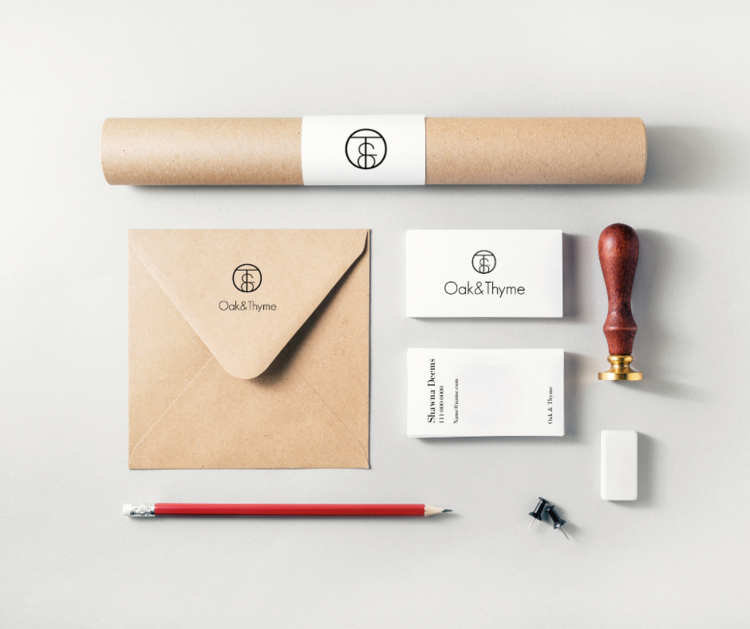 Stationery items arranged on a white background, including a brown paper scroll, an envelope, two boxes of business cards labeled "Oak & Thyme," a sealing stamp with a wooden handle, a white eraser, a red pencil, and a small black pushpin.
