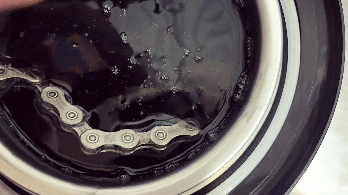 View inside a washing machine drum with black water, a chain, and soap bubbles.
