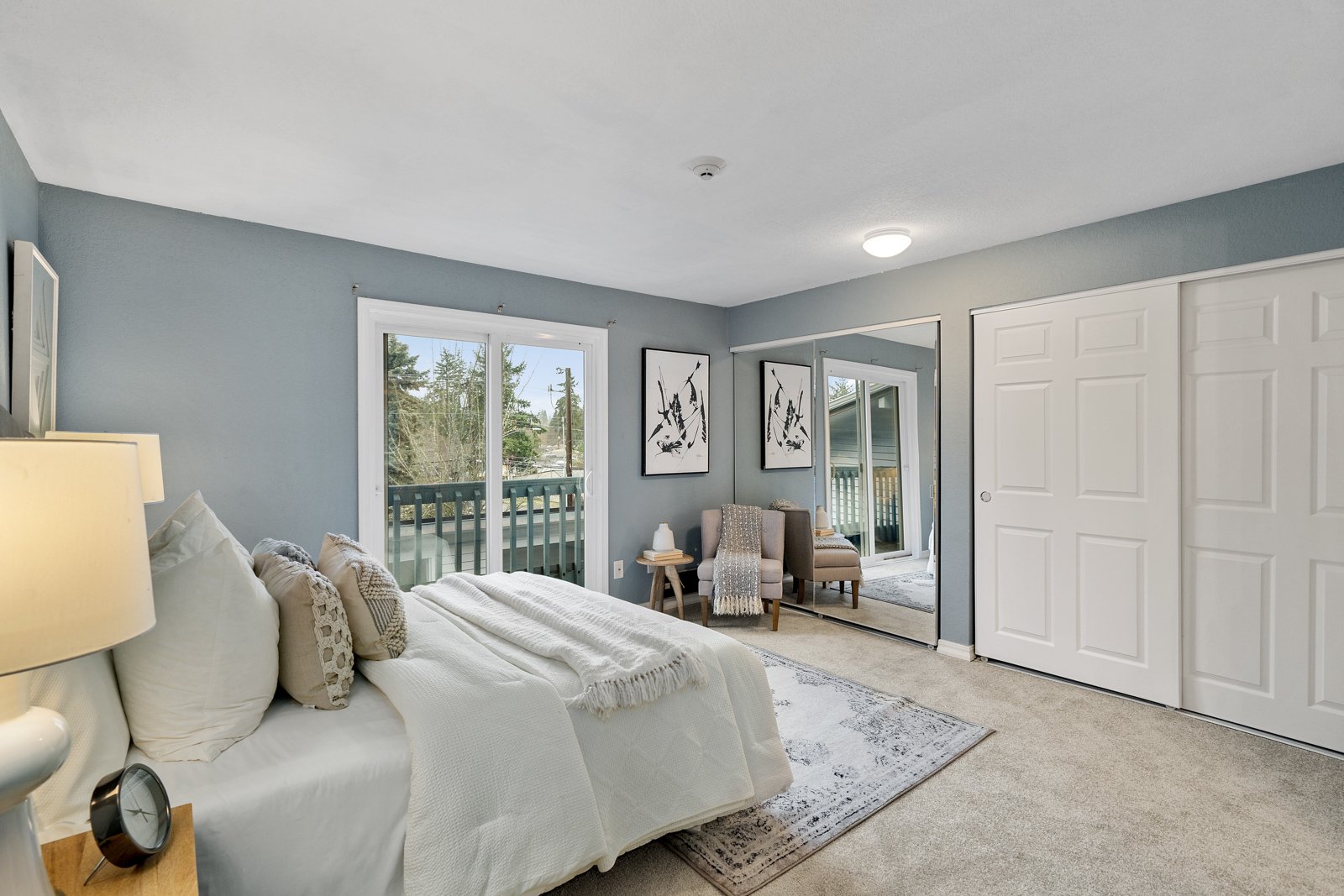 interior of bedroom with large closet, bed, chair, and doors to balcony