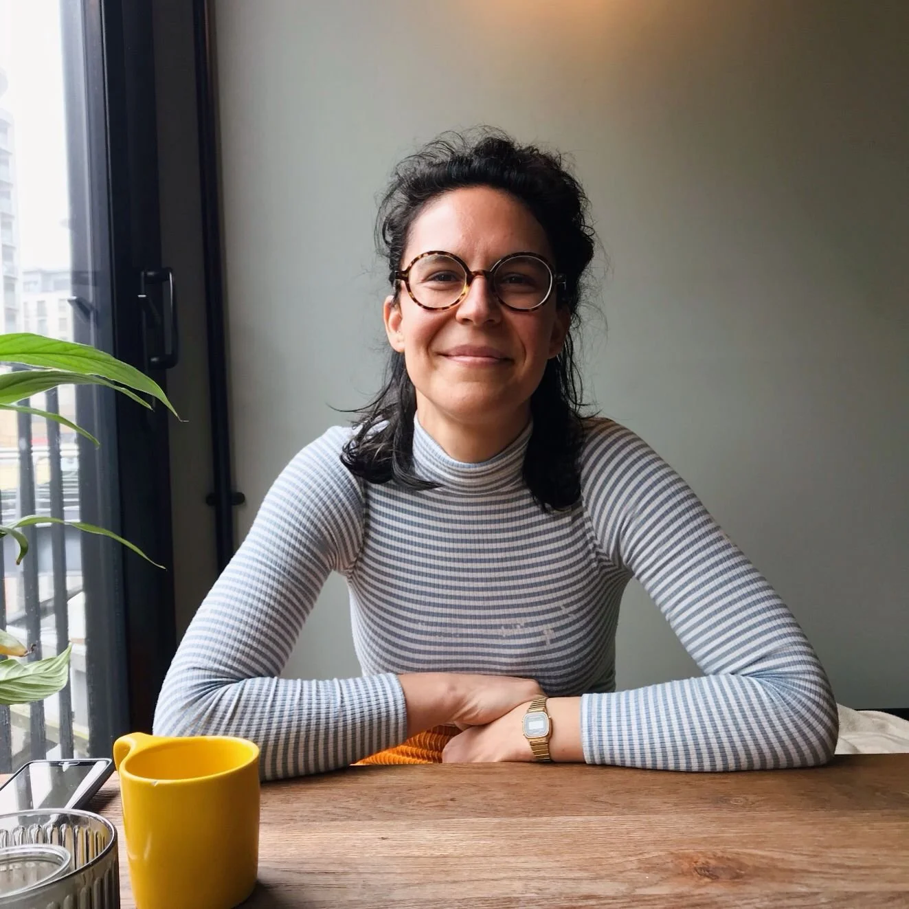 Smiling Michaela wearing a white and blue stripes top and orange trousers.