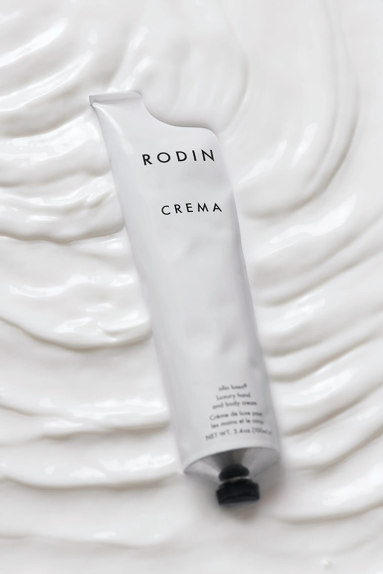 Rodin hand cream tube floating in a pool of milk