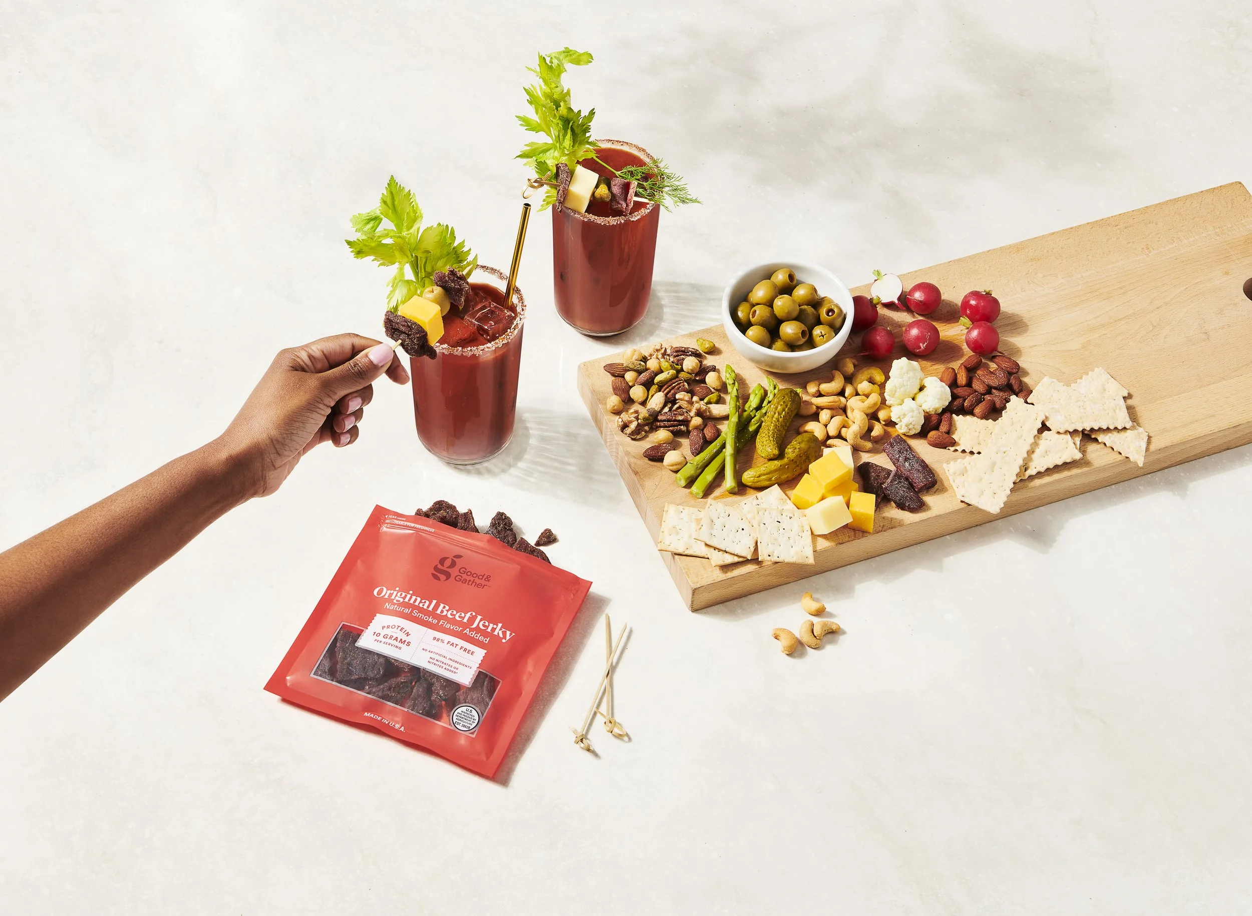 charcutterie board with meats cheese bloody marys crackers and vegetables