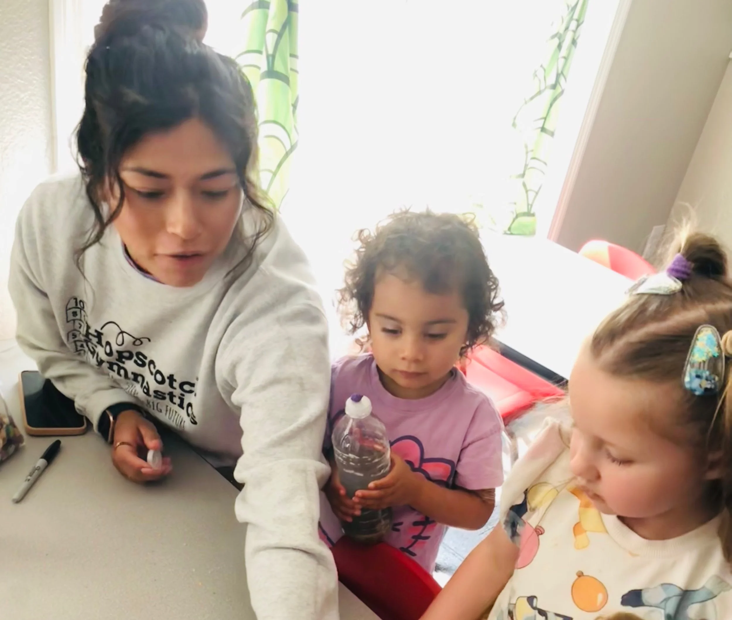 A woman teaches young students how to build ocean-themed sensory bottles.