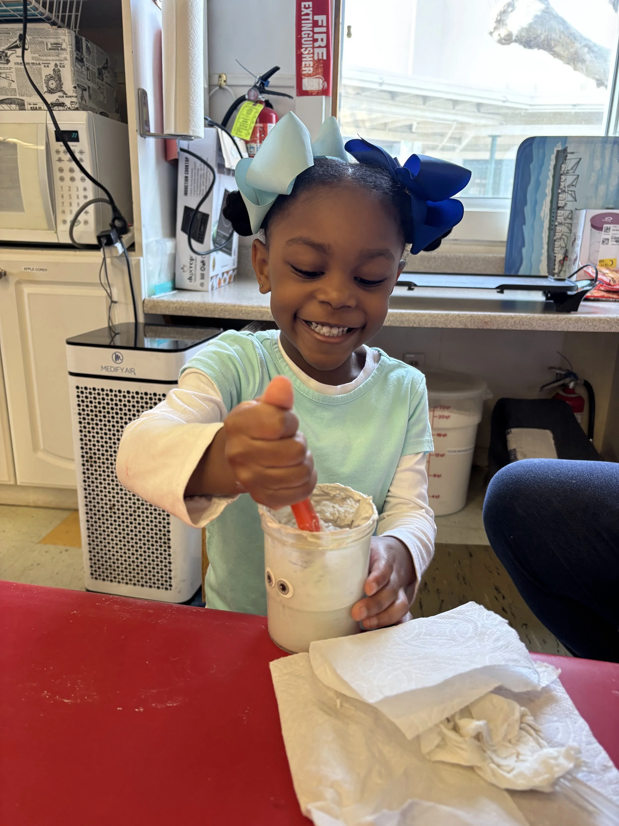 A girl mixes contents with a brush in a plastic cup