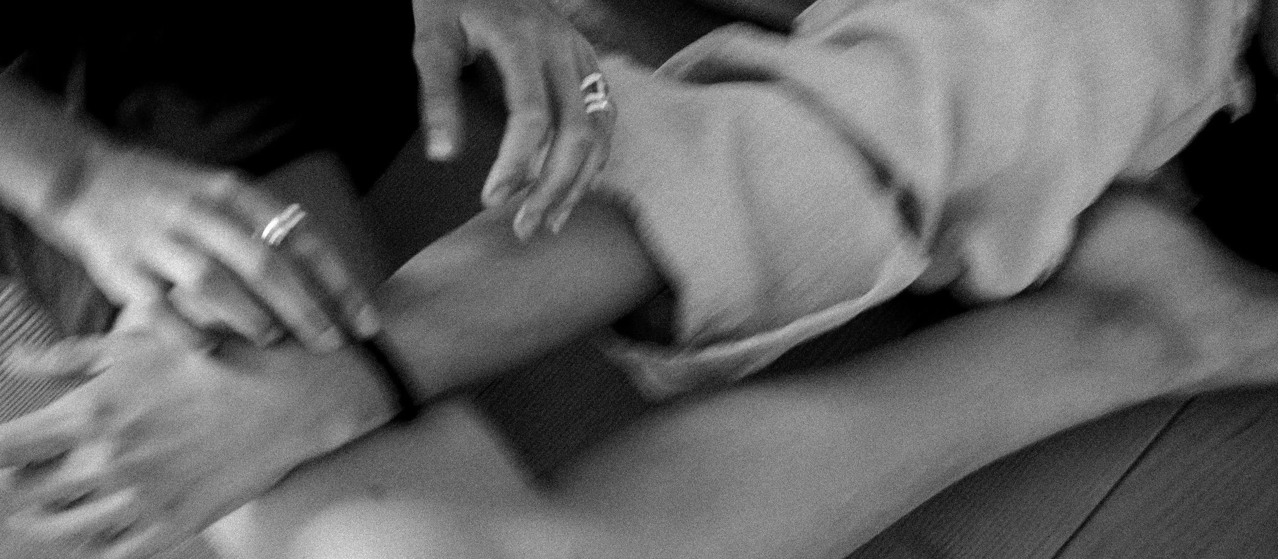 Zwei Menschen beim sanften Kontakt, möglicherweise eine Massage, auf einem Boden mit Yoga- oder Gymnastikmatten.