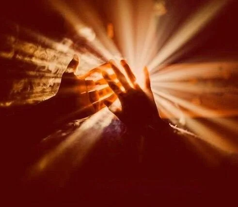 Two hands touching with light rays radiating outward from the contact point.
