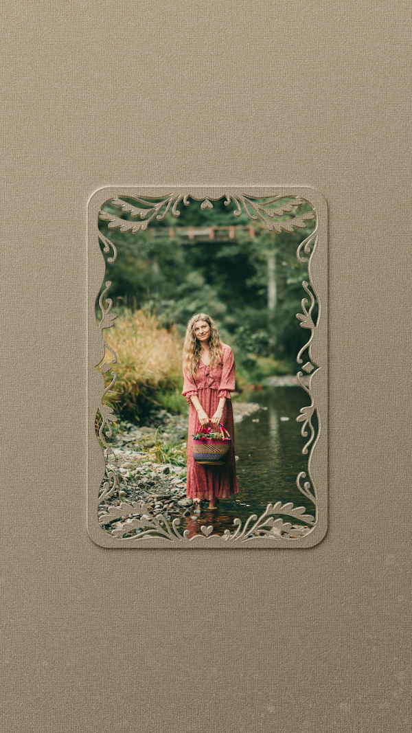 A framed photo of Madeline Giles standing in a creek, holding a basket, surrounded by trees and greenery.