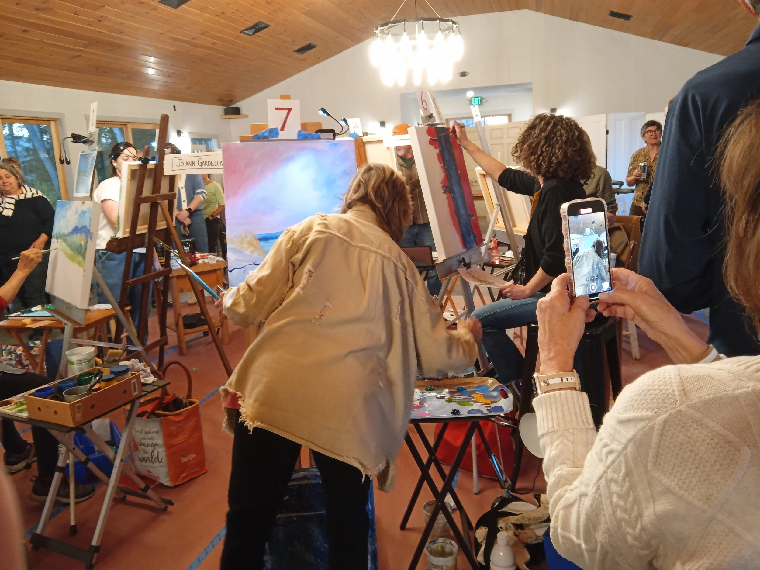 Woman painting soft pastel painting on canvas on an easel.