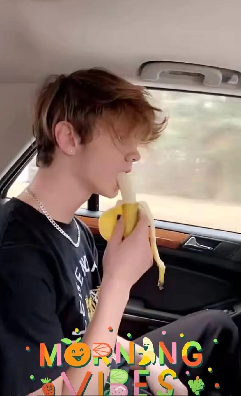 Person in car eating a banana with 'Morning Vibes' text overlay.