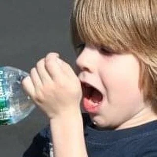 Child laughing with a bottle of water