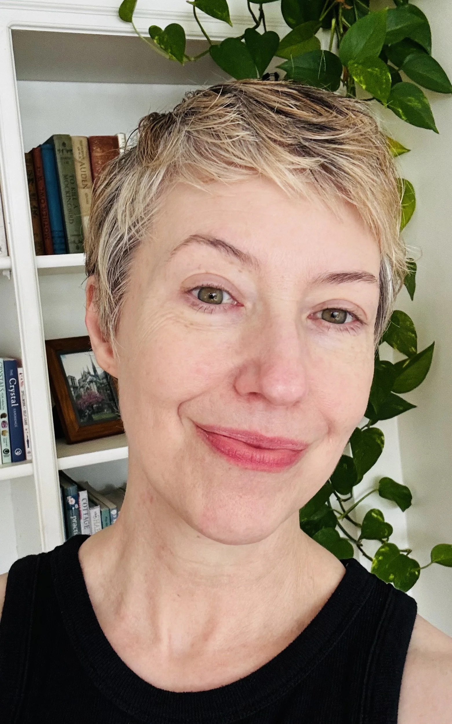An image of Ashburn’s Sthira Sukham Yoga teacher, Sara Charbonneau-Sider; she has short blond hair, is wearing a black sleeveless shirt, and a soft smile.