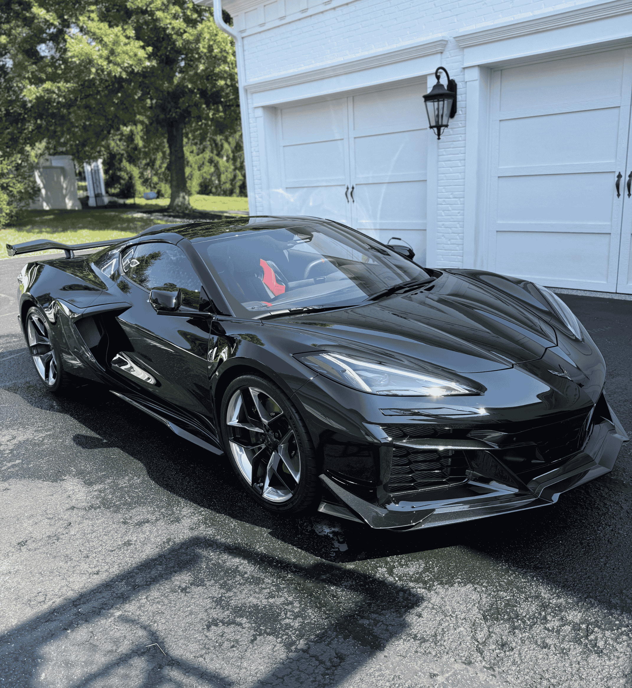 A sleek black Corvette C8 sports car with a high-gloss finish parked on a residential driveway in Northern Kentucky after a professional mobile exterior detail.