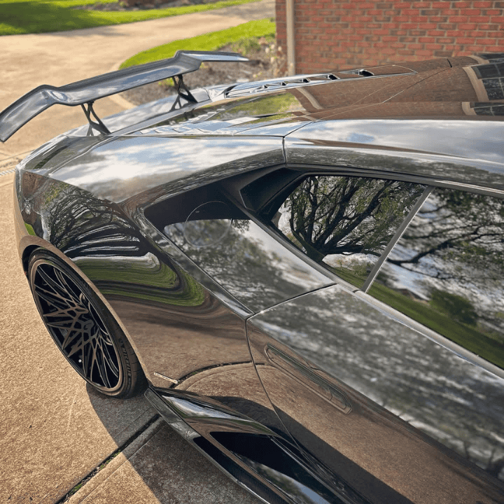 Side profile of a high-end black sports car with a mirror-like reflective finish, demonstrating professional paint enhancement and clarity achieved in the Cincinnati region.