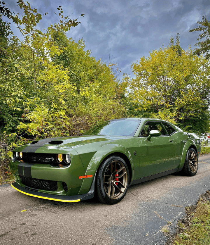  A forest green Dodge Challenger Widebody parked on a scenic road in Cincinnati, highlighting a clean, high-gloss exterior and aggressive profile.