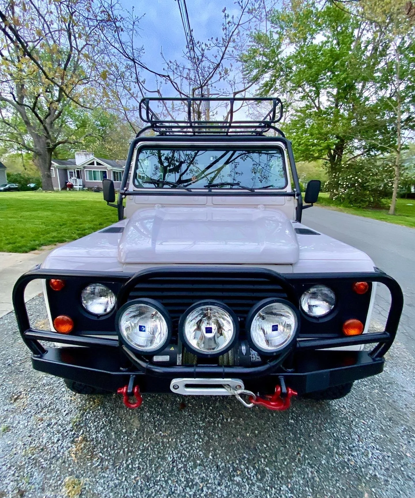 A white Land Rover Defender off-road vehicle parked on a residential street in Northern Kentucky, showcasing a pristine, high-gloss finish after a professional Full Signature Detailing service.
