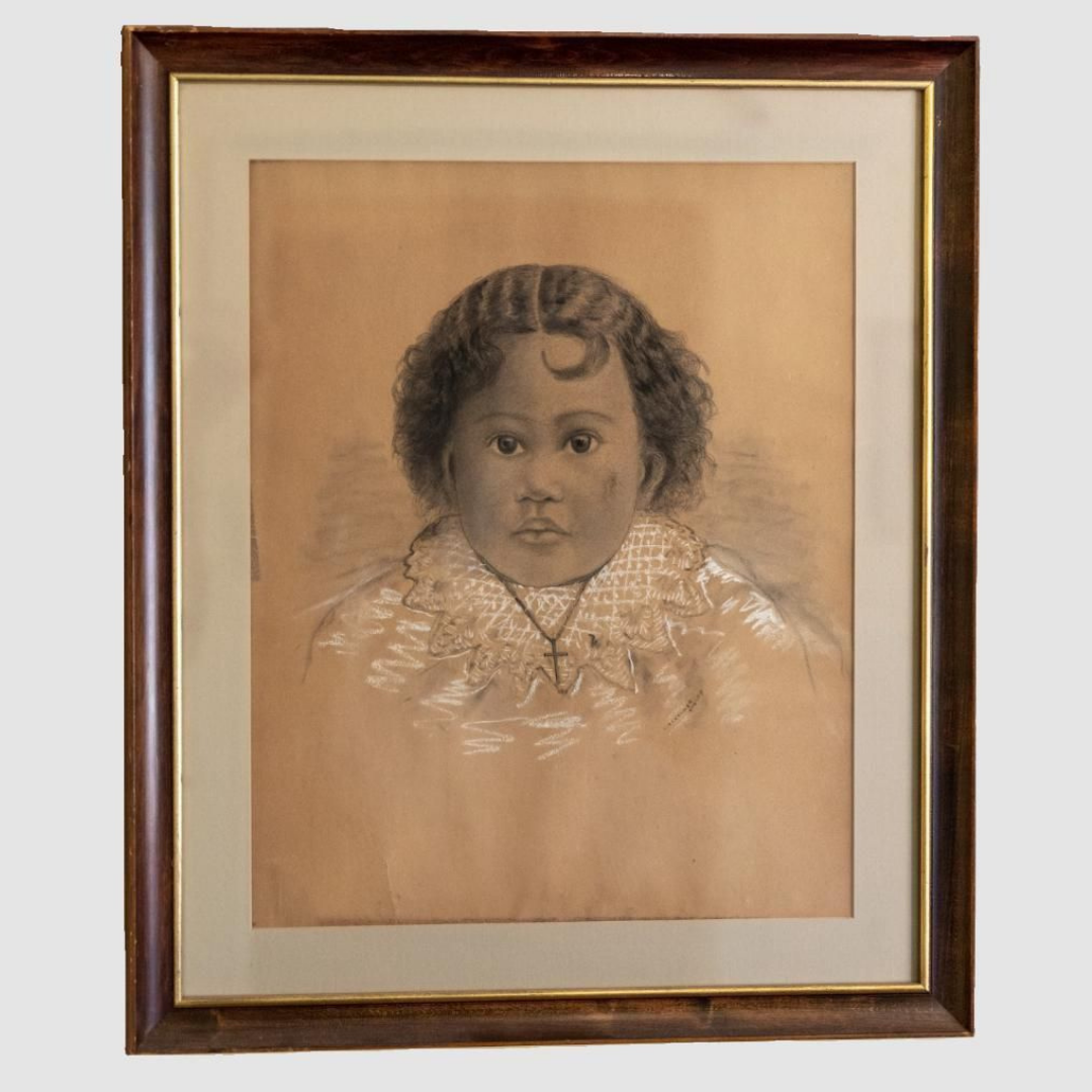 A framed pencil or charcoal portrait of a young child with curly hair, wearing a lace-collared outfit and a necklace with a cross pendant.