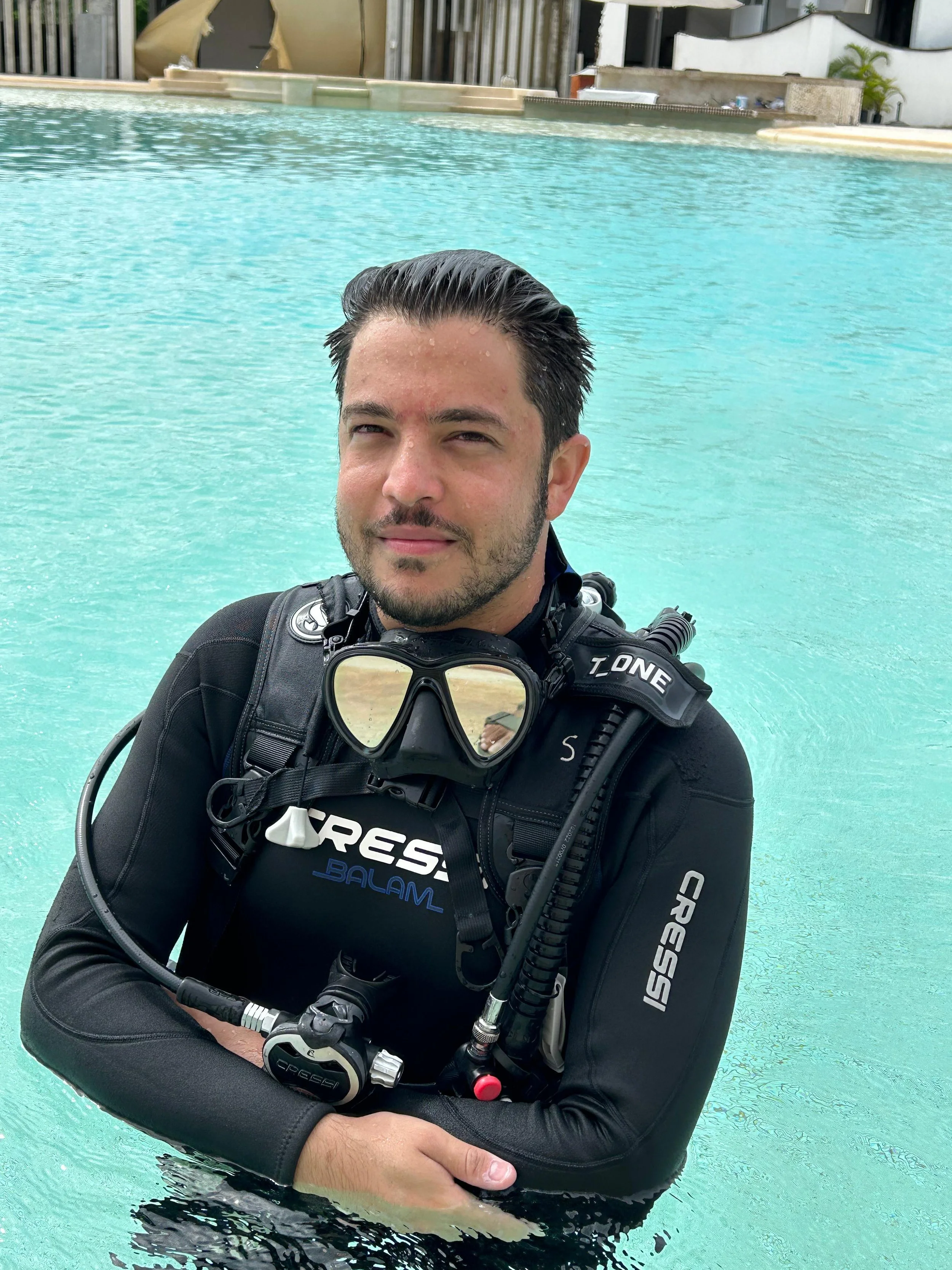 A man in scuba diving gear standing in a swimming pool.