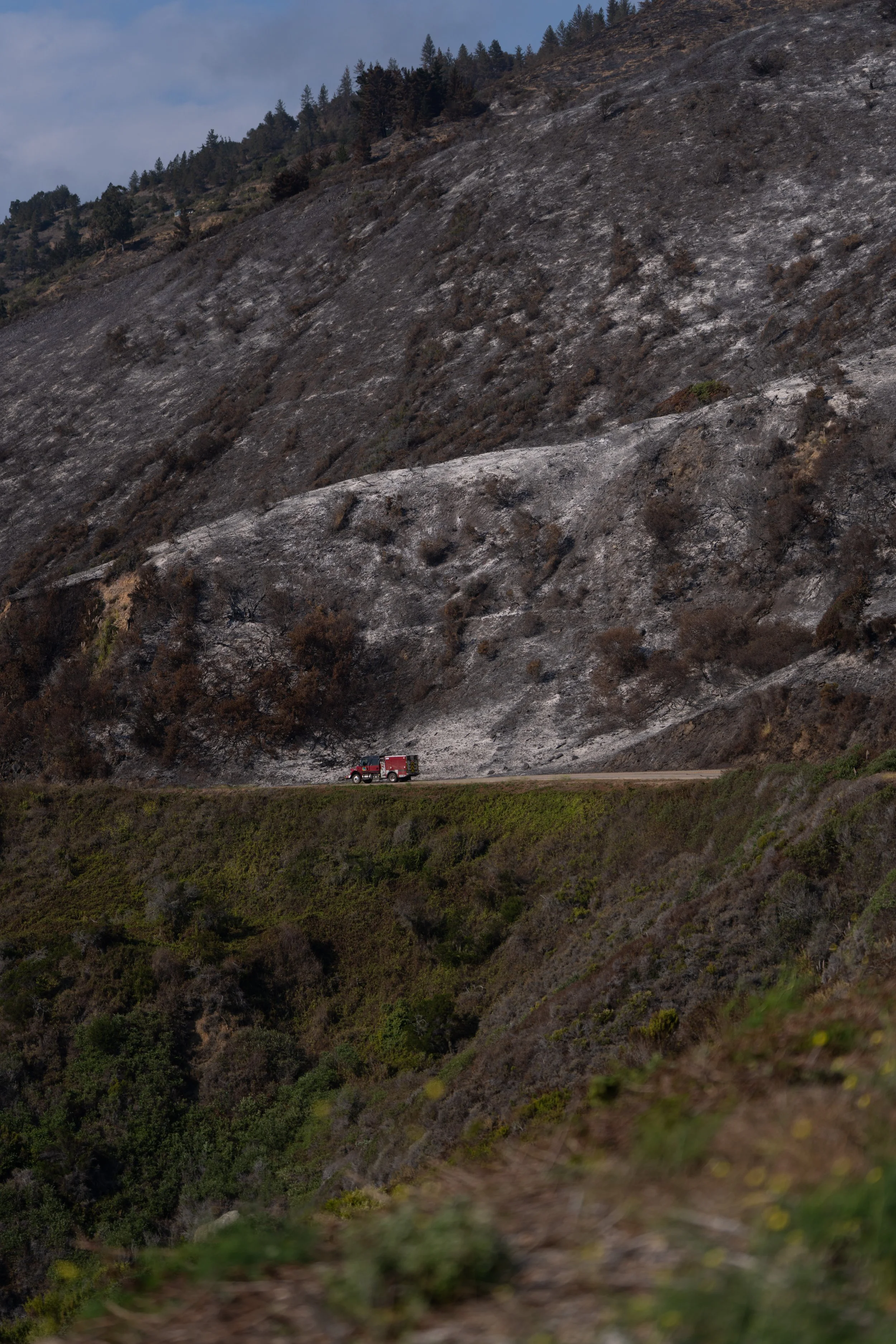 A fire engine travels along Highway 1 below a hillside burned by the Plaskett Fire near Plaskett in Big Sur, Calif., Friday, Sept. 4, 2026.
