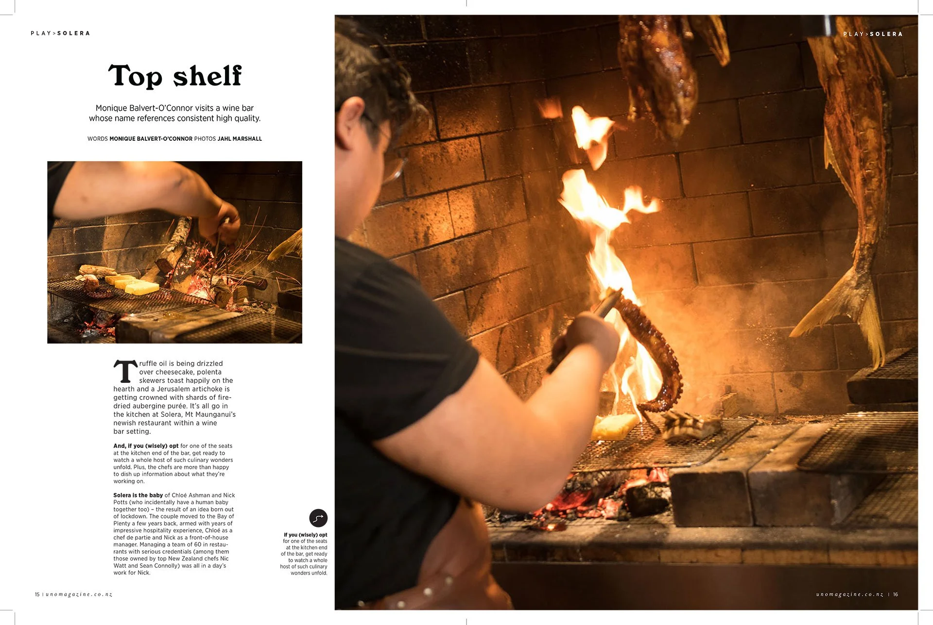 Person grilling octopus tentacle over open flame inside a brick oven.