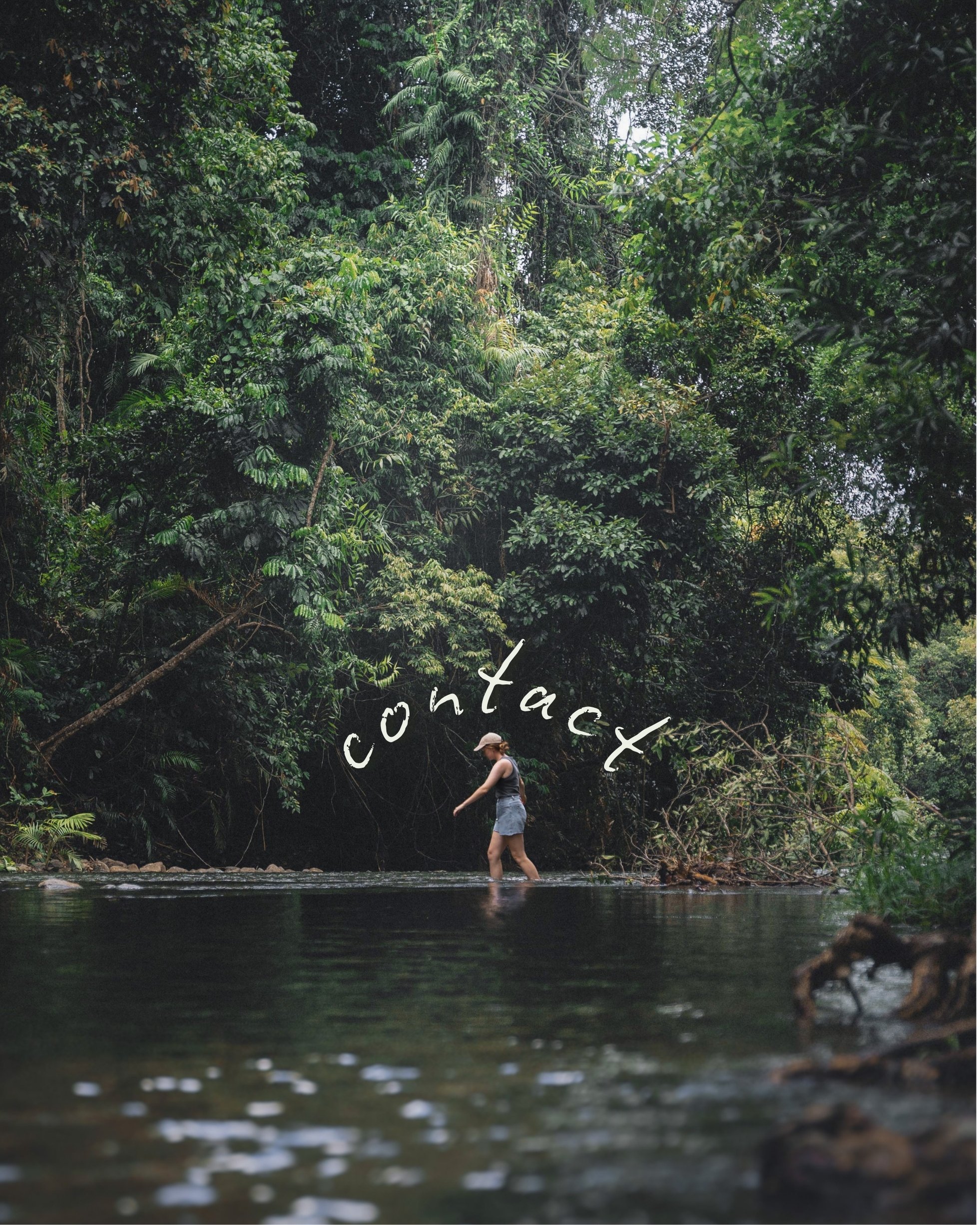 Woman walking across a creek in the rainforest with text "CONTACT" written above