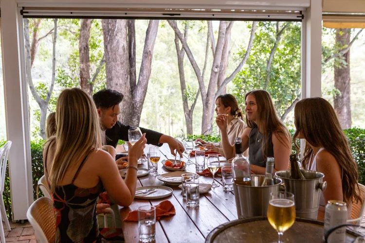 Guests enjoying a wine tasting around an outdoor dining table