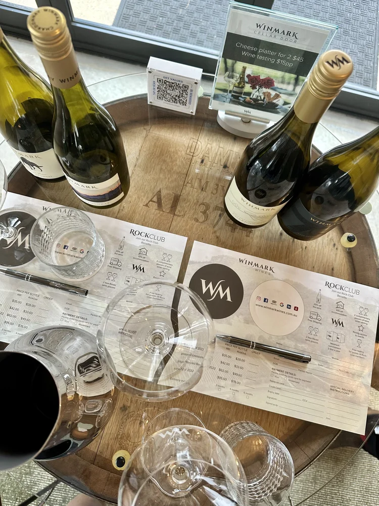 Winmark wine bottles, glasses and tasting notes on a table