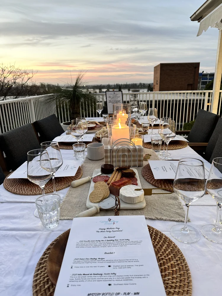 A candlelit outdoor table set with wine glasses and tasting notes