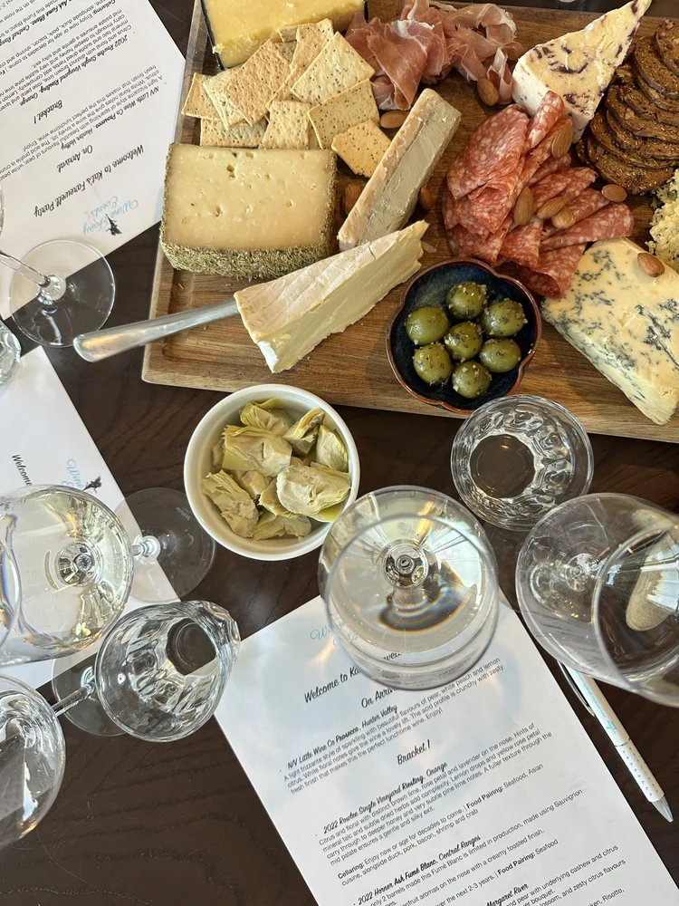 Cheeses, olives and wine glasses arranged for a wine and cheese tasting