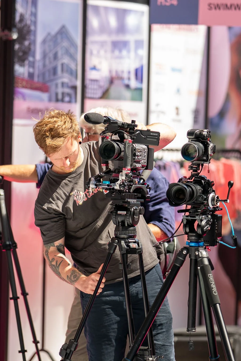 A man is setting up his tripod with a camera on at the foot of the catwalk at London Olympia