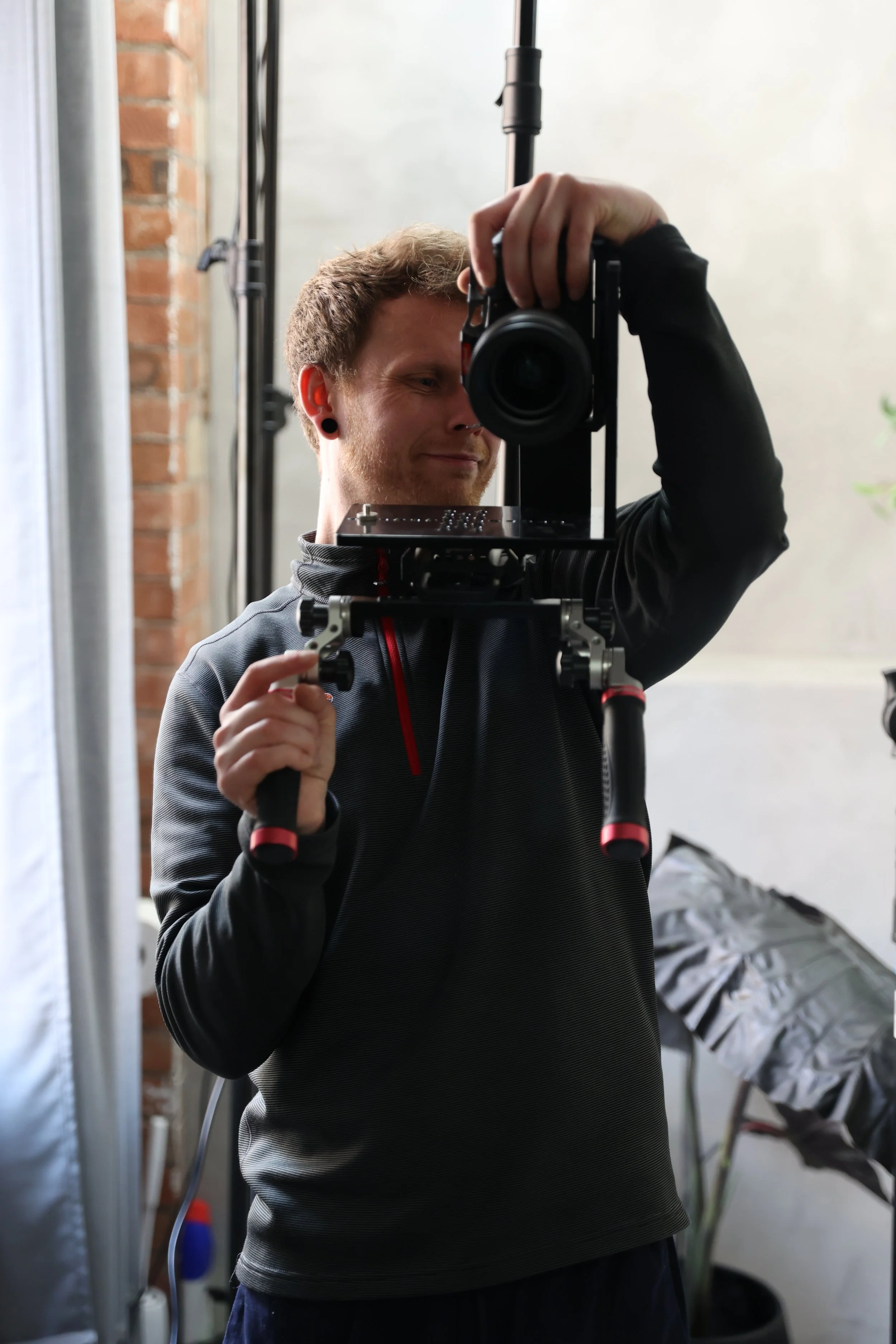 An image of Thomas Stanley in the mirror, posing for the vertical camera rig he is holding in East London on a shoot in a location for a lifestyle brand. 