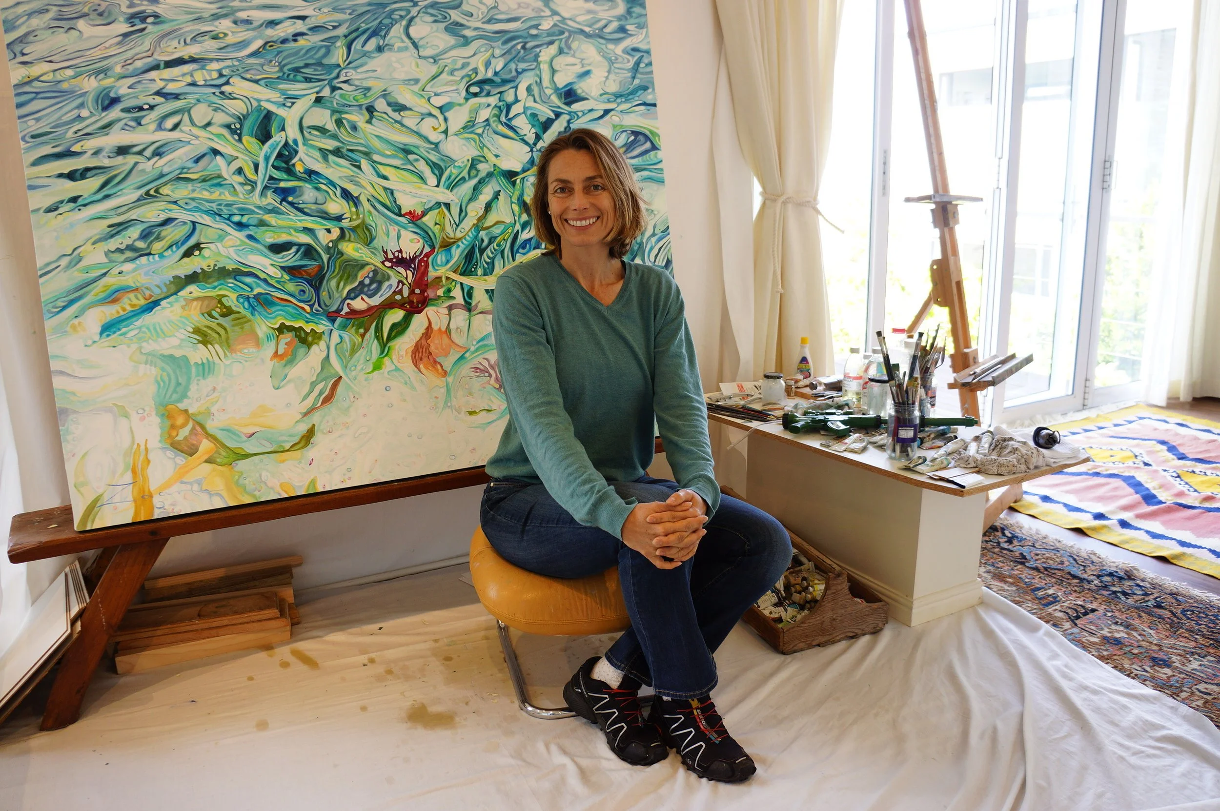 Zaan Claassens with her oil painting Vibrant Ocean in her CampsBay Studio.jpeg