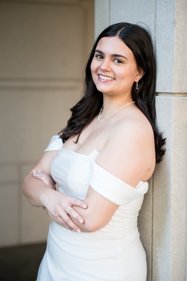  senior graduation photos of graduate in white dress leaning against column 