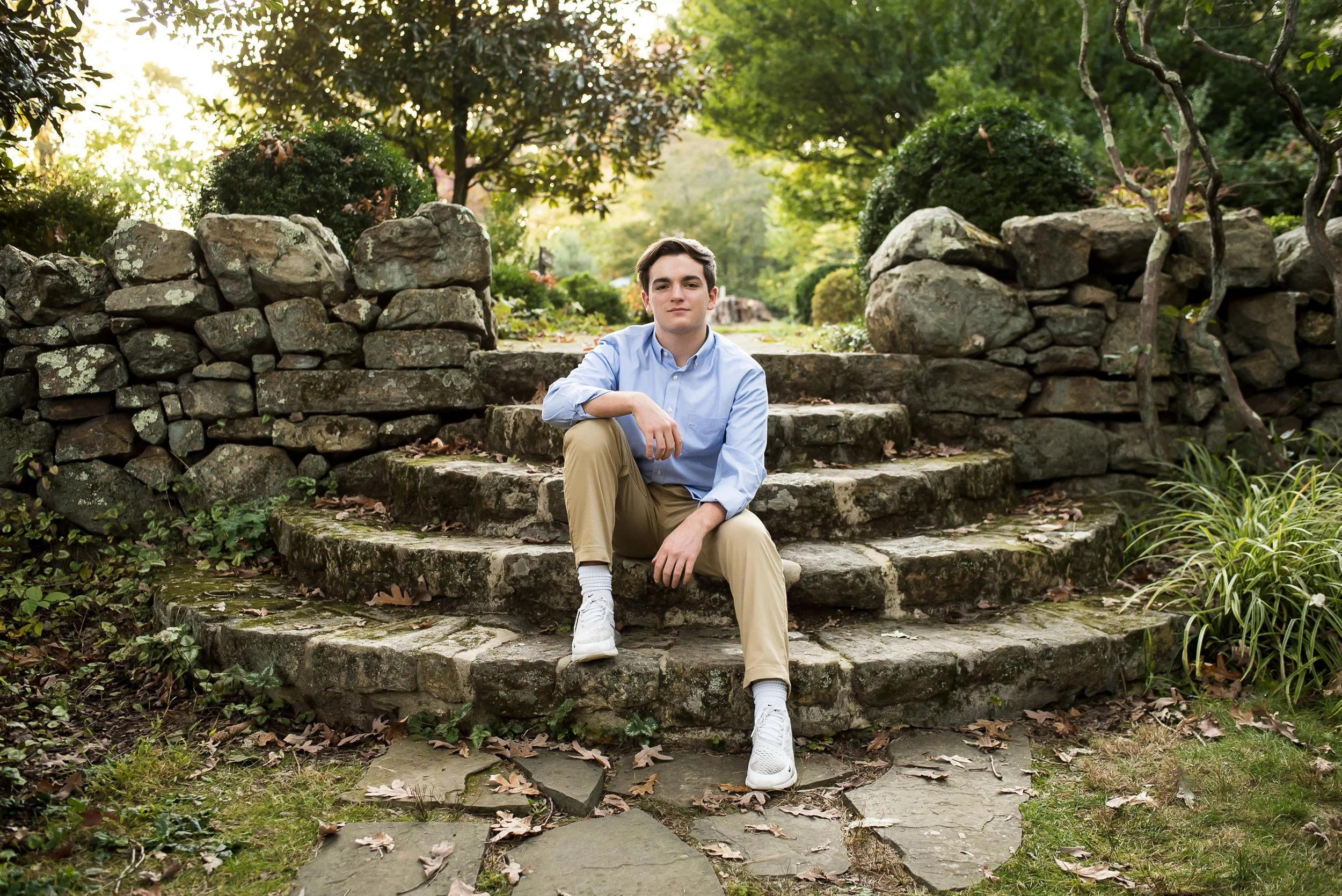  natural senior portrait of male graduate sitting on stone steps outdoors 