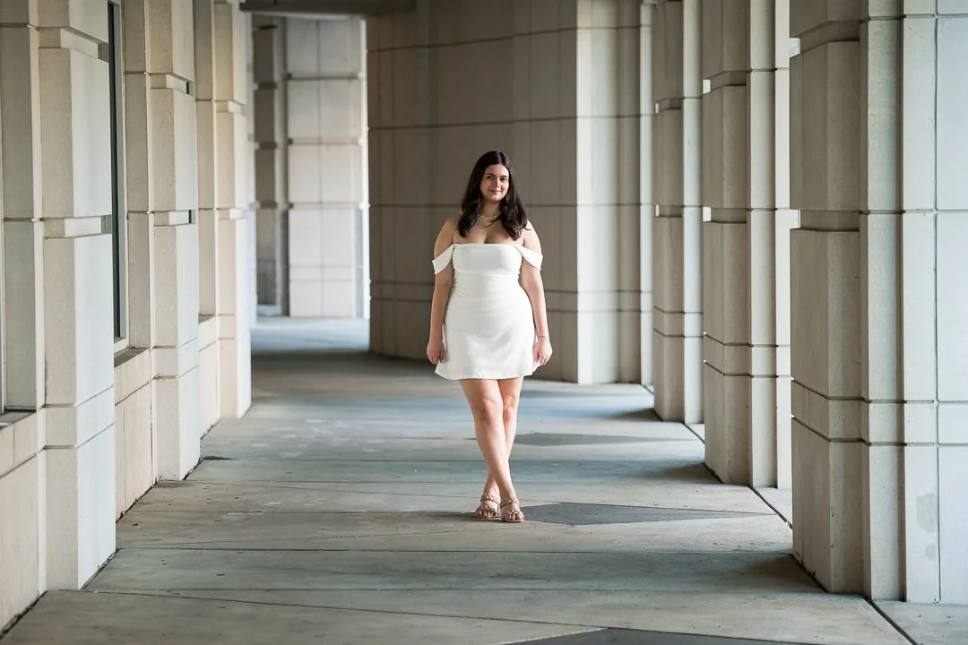  senior portrait walking through architectural columns in white dress 