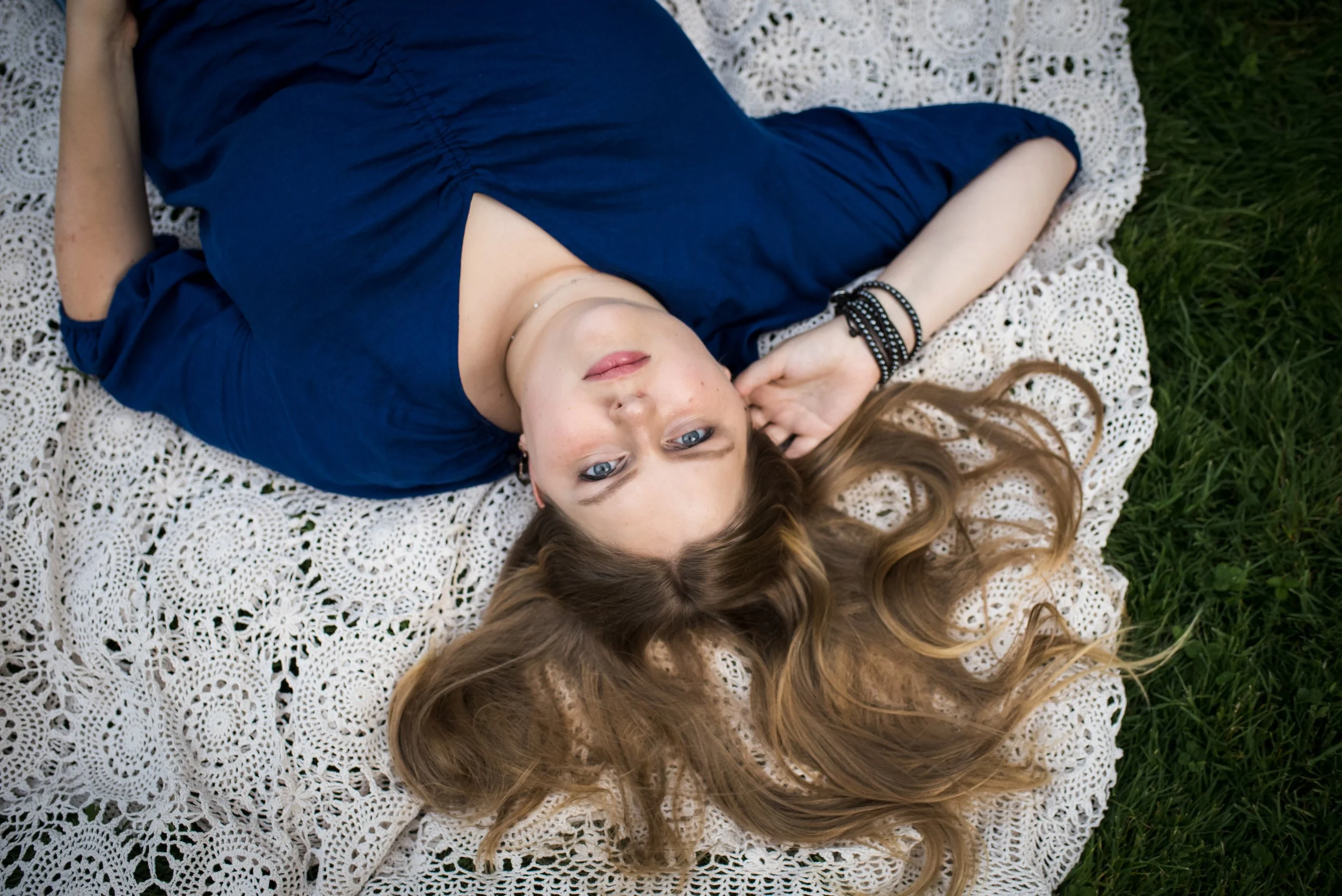  overhead senior portrait laying on blanket outdoors with book 