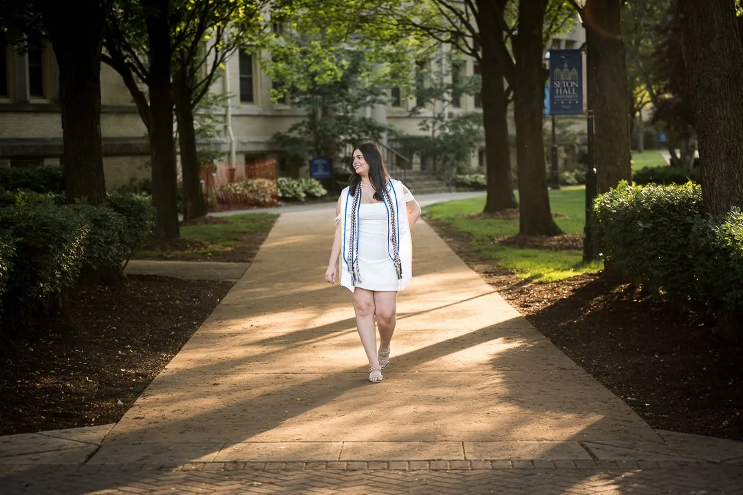  senior graduation photos walking on campus path with trees and sunlight 