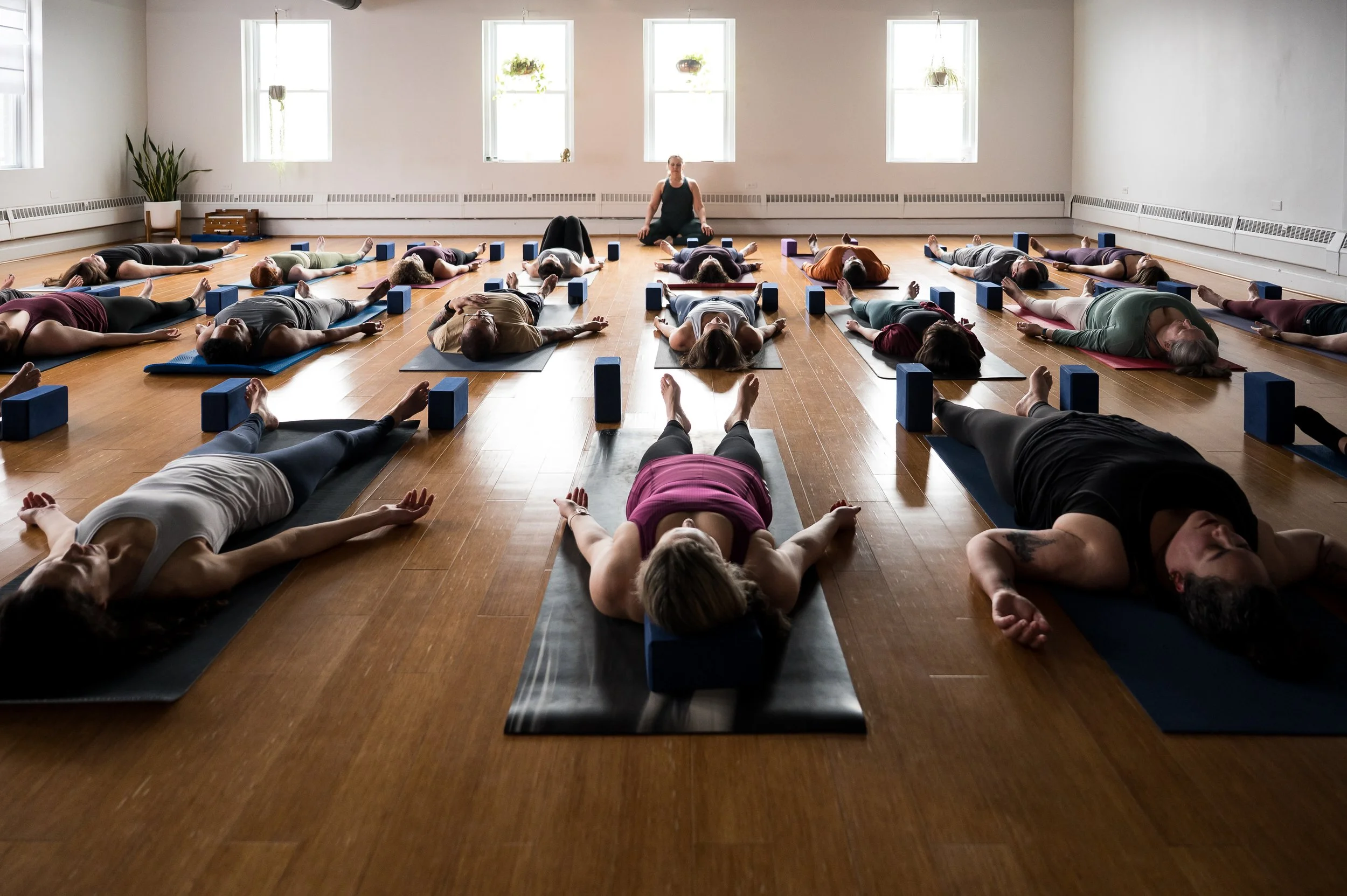 Wide photo of a group yoga class at Three Birds Yoga Studio showing students in warrior pose