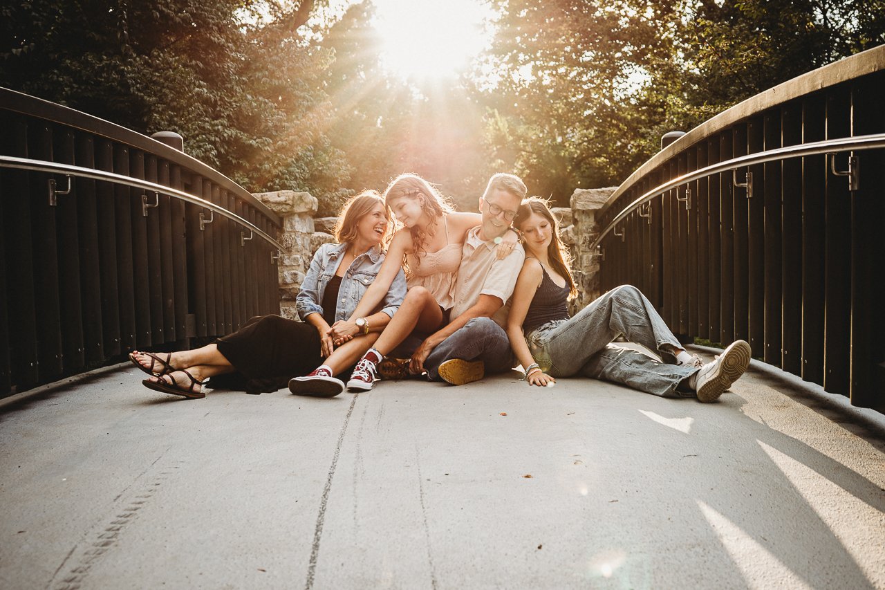 a family of four sitting on a bridge during sunset