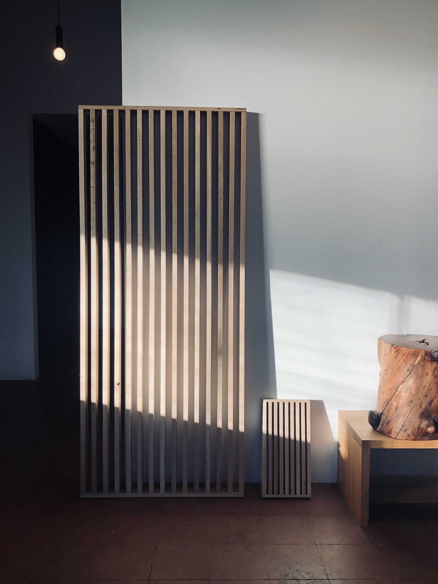 Light falls across a slatted wood wall screen made by Material Studios