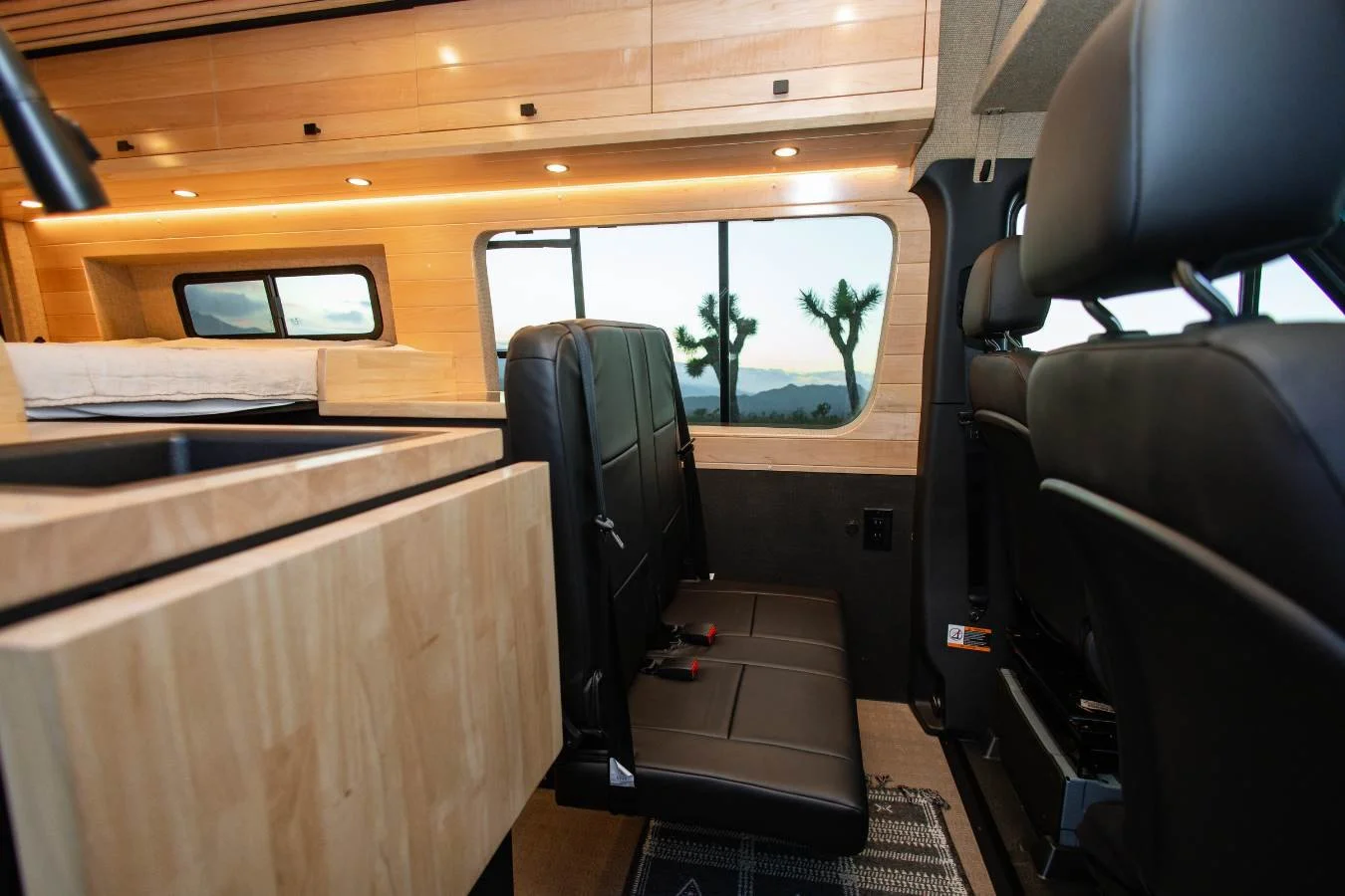 Second row seating area and galley view inside modern luxury camper van interior.