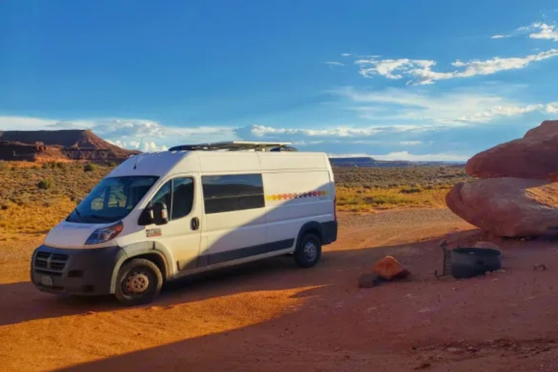 White custom conversion van parked in a desert landscape, representing the best conversion van rental option in Burlington, Vermont.