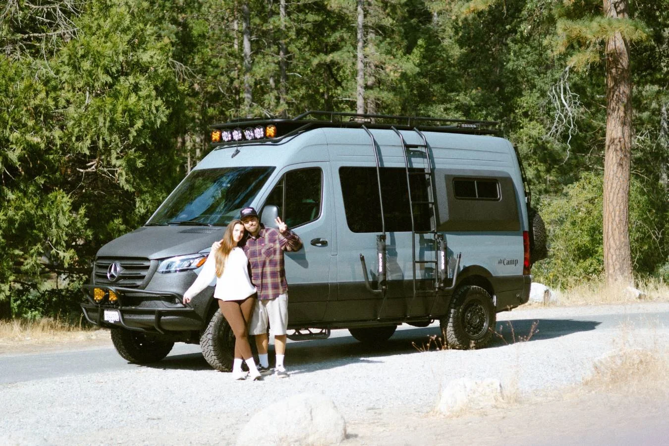 Couple standing next to luxury 2025 Mercedes Sprinter camper van near Yosemite campsite