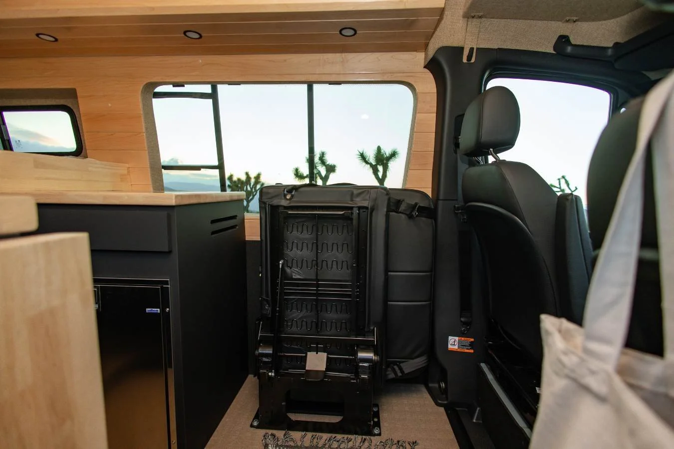 Second row folding seating area and galley view inside modern luxury camper van rental