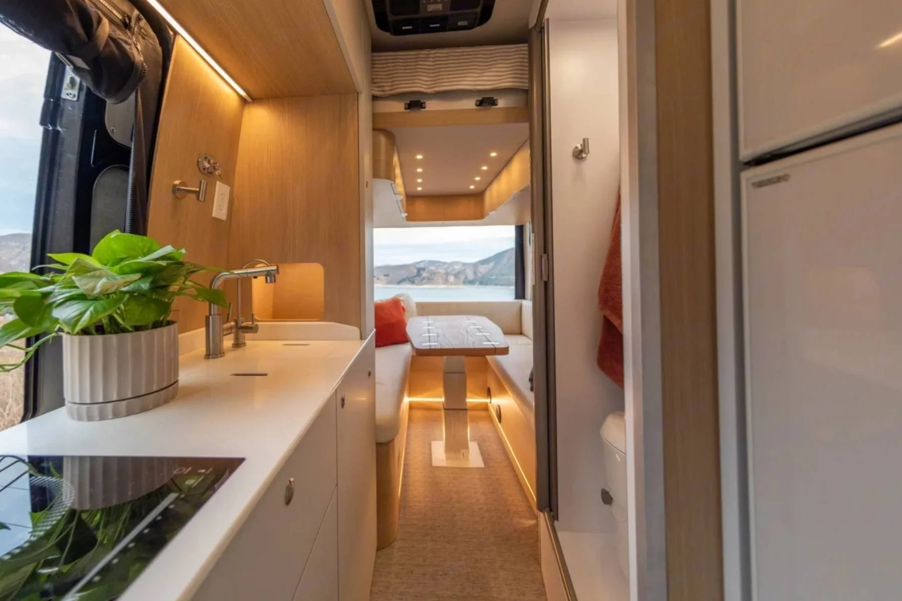 Luxury conversion van interior in New Mexico with modern kitchen, workspace, and lift bed by Noovo