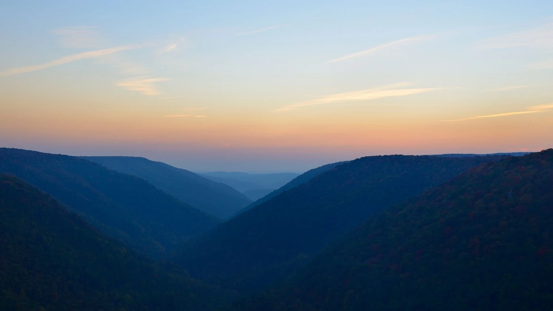 Mountain ridgelines and river gorges in West Virginia at sunset, a scenic backdrop for camper van rentals and Appalachian road trips.