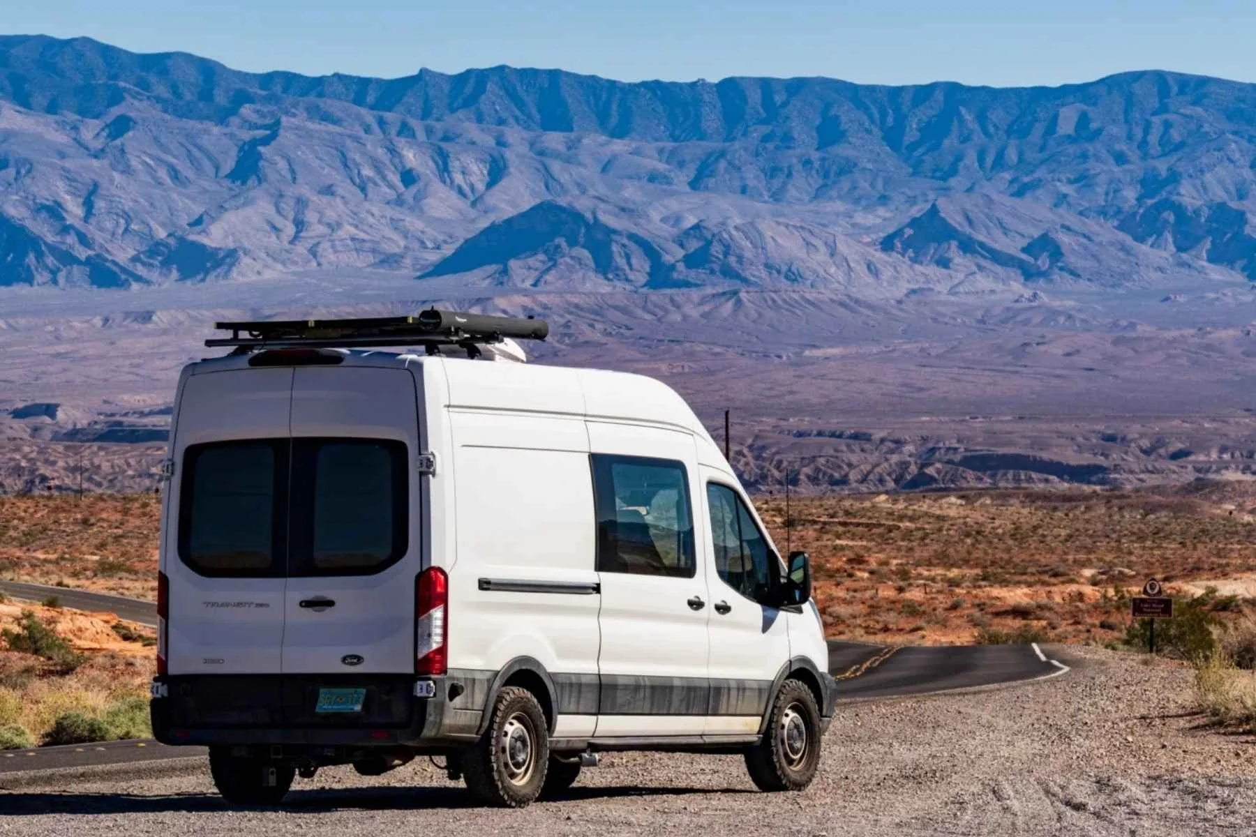 White camper van rental parked on a desert road in New Mexico with mountain backdrop
