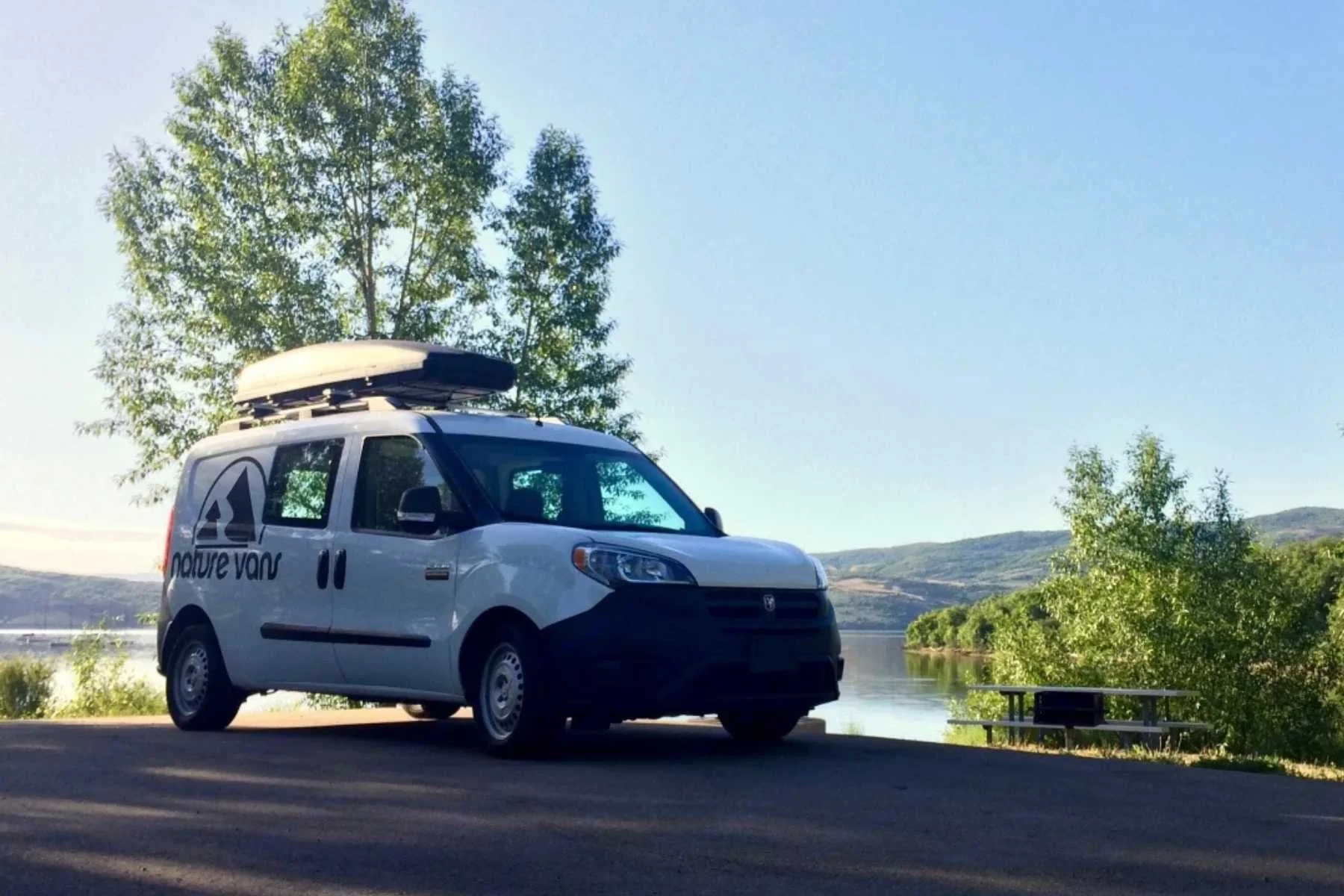 Budget campervan rental in Salt Lake City featuring a ProMaster City van parked by a Utah lake, ideal for affordable Mighty 5 national park road trips.