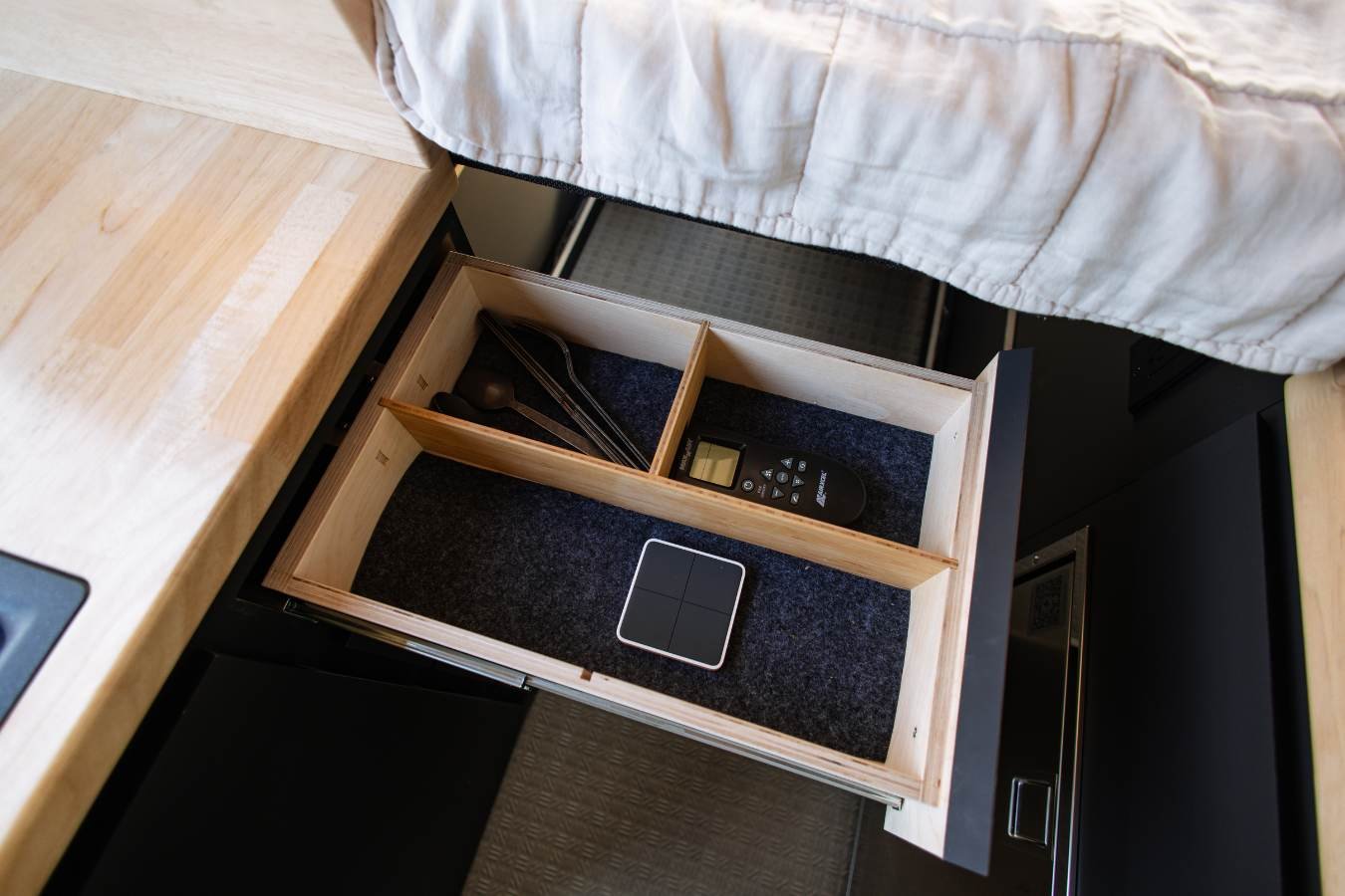 Organized drawer storage inside luxury Sprinter camper van kitchen.