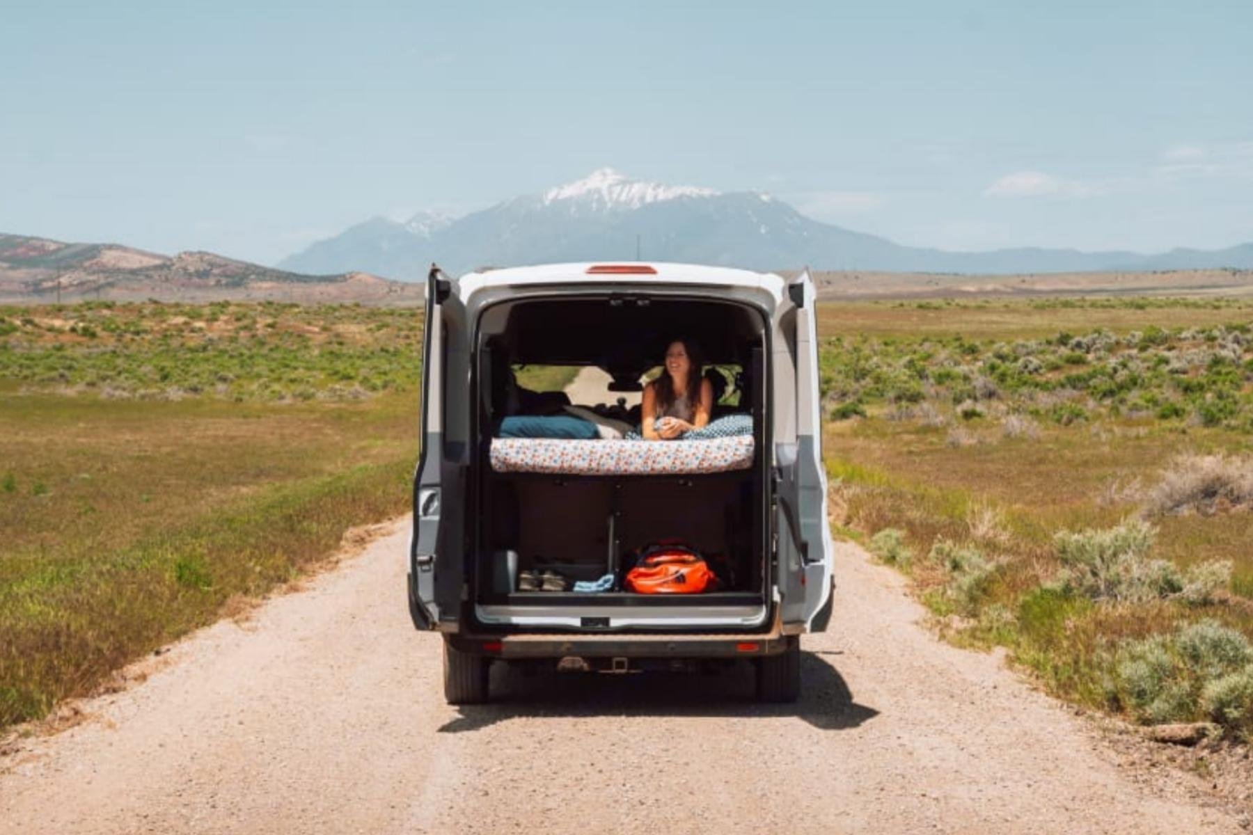 Budget Ford Transit camper van rental in Bend, Oregon with rear bed setup and mid-roof design